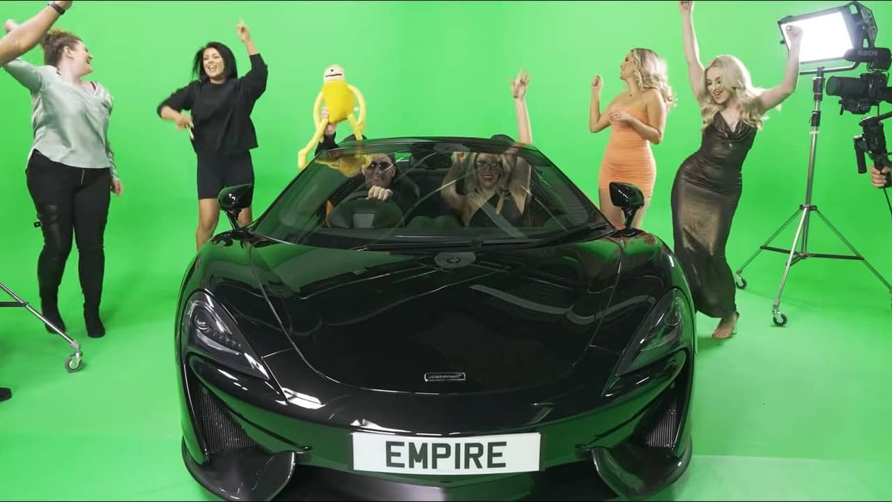 Crew and performers on a green screen set filming a music video around a black sports car