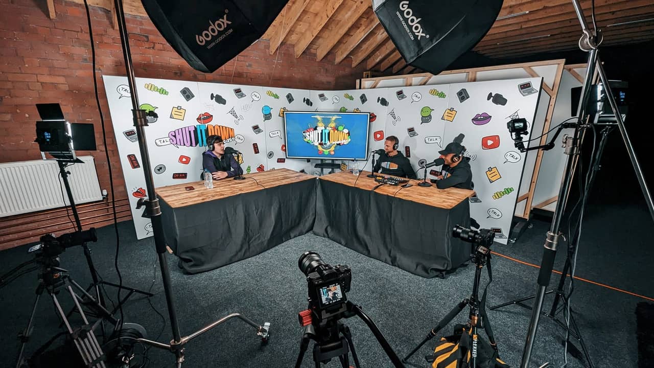 Three hosts recording a podcast at the branded Shut It Down desk in Flexxed’s studio