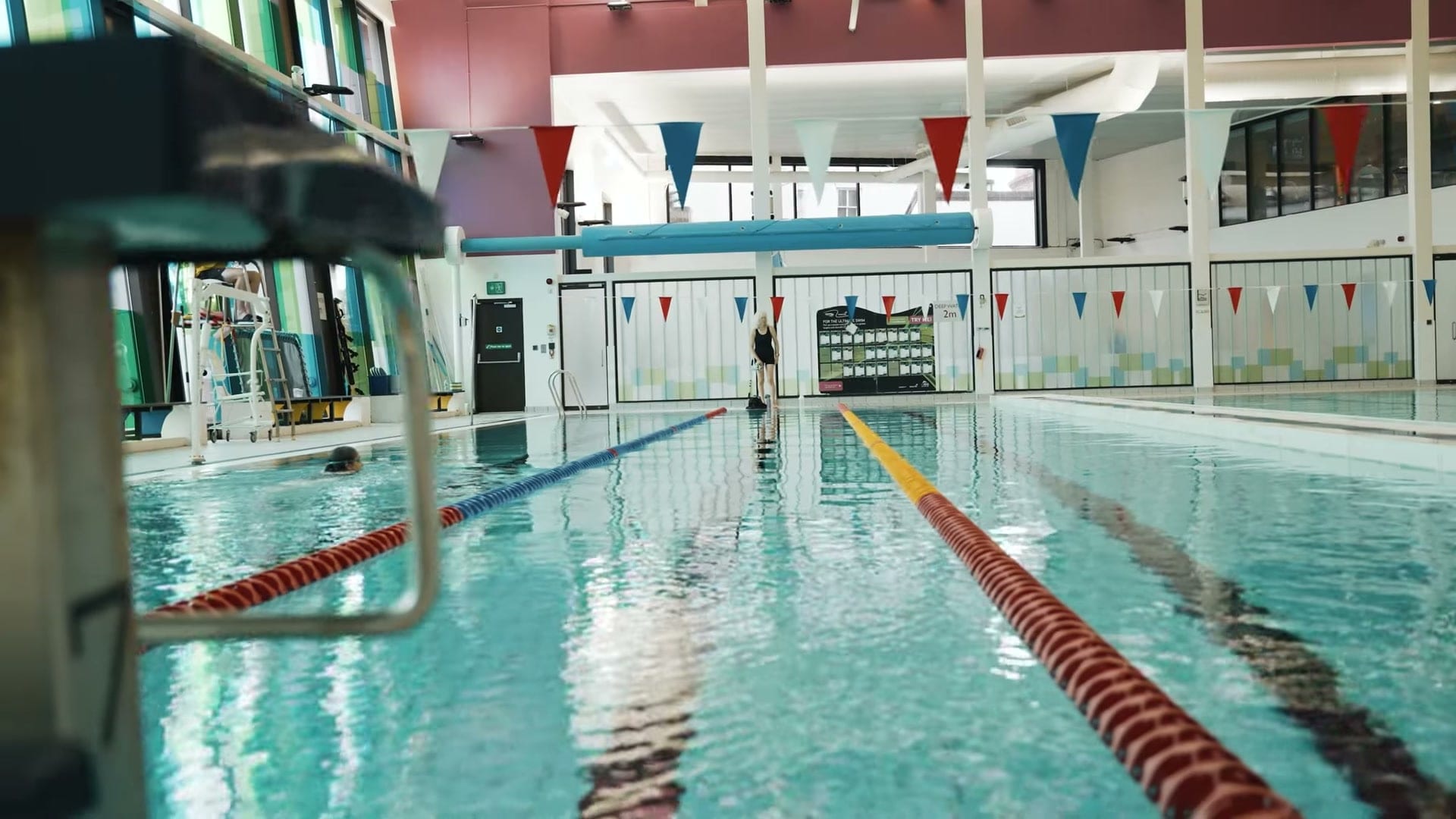 A swimmer in the lanes of a BwD Leisure pool, bunting strung across the hall, from the Turn Up The Heat film