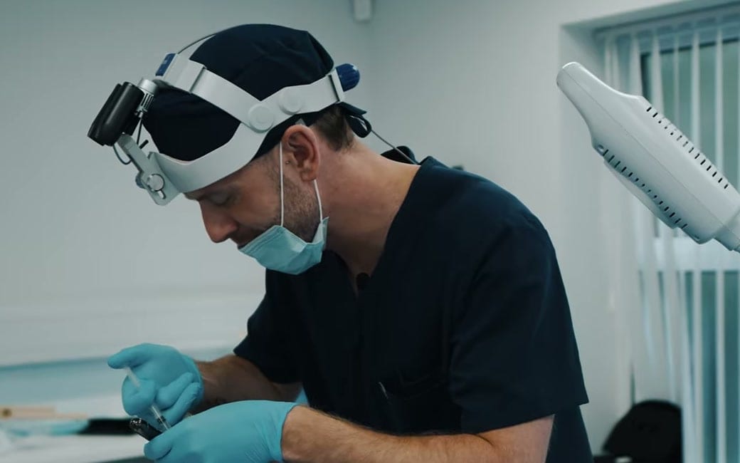 A clinician in a surgical cap, loupes and gloves preparing a treatment at The Rejuvenation Doctors in Bury