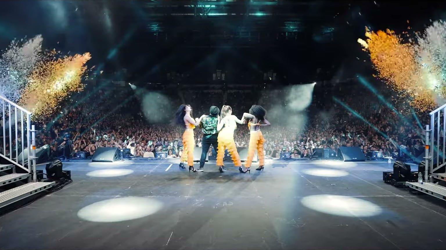 Performers on stage facing a packed AO Arena crowd as confetti cannons fire, from the 90s Baby POP after movie