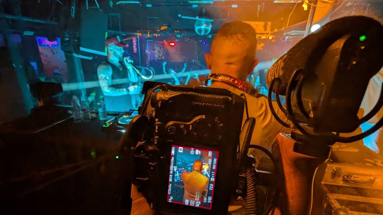 Filming a club night from the stage, the camera monitor framing the MC under orange and blue light