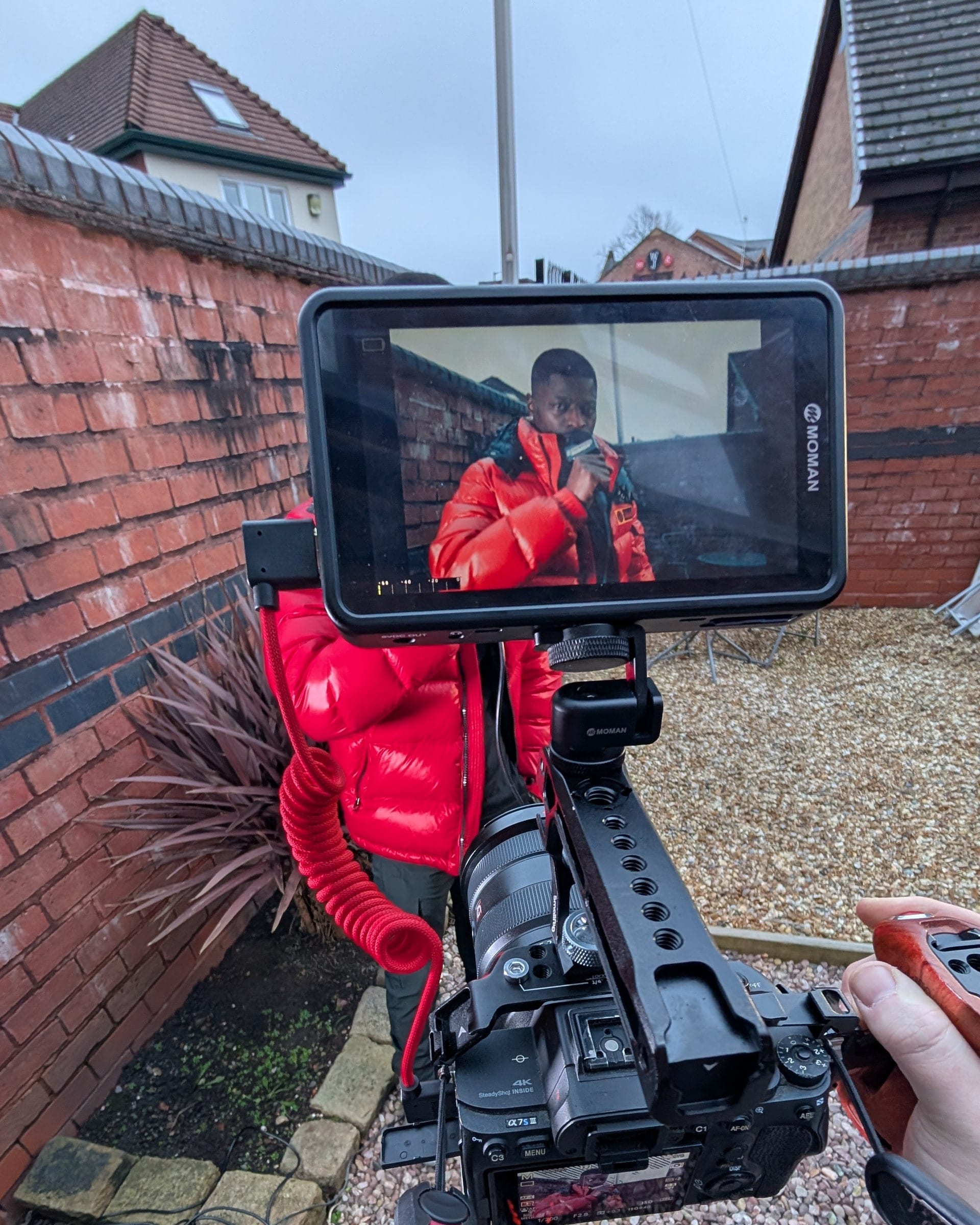 On-location music video shoot: an artist in a red puffer jacket framed on the camera monitor