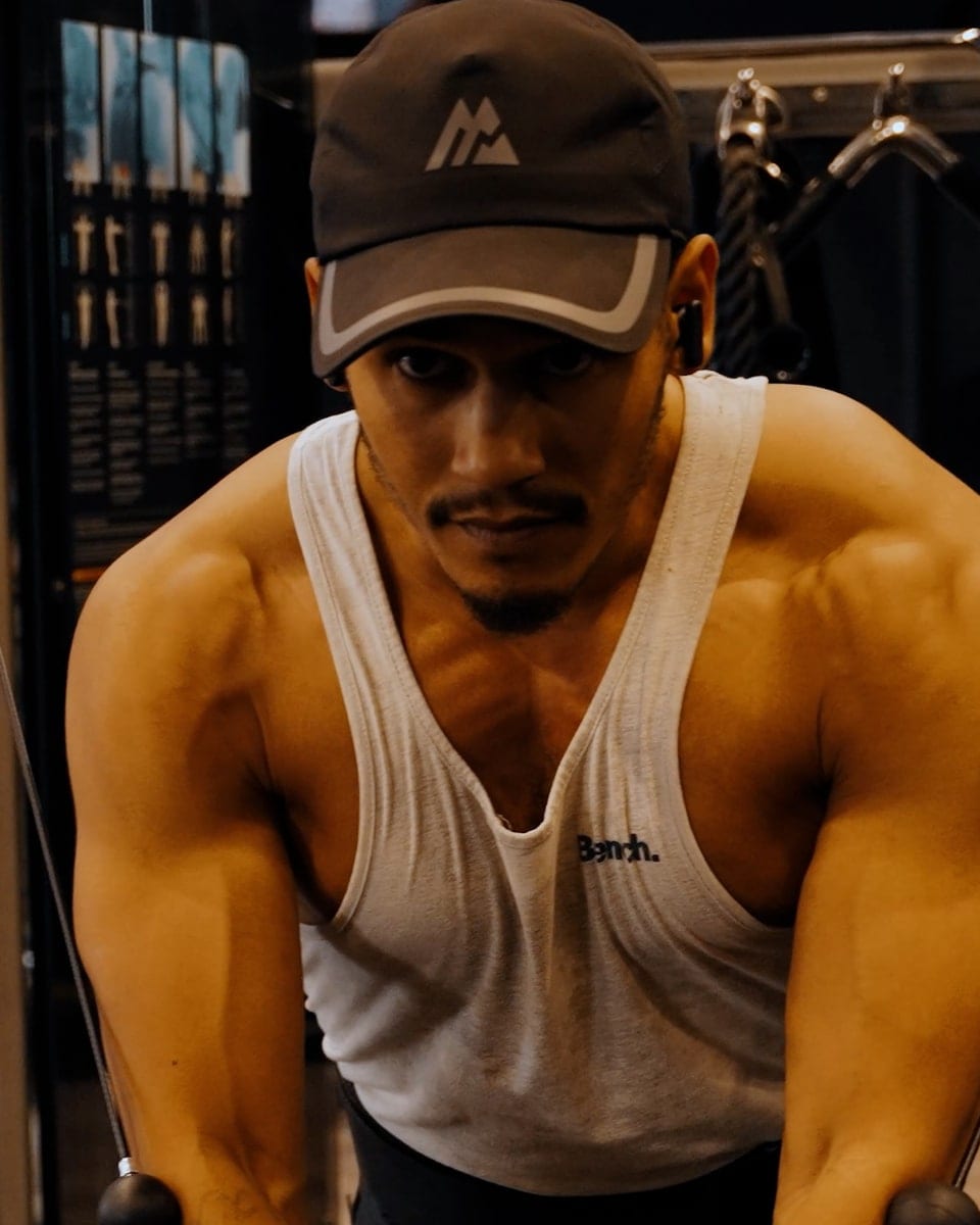 A man in a vest mid rep on a gym machine, shot for a fitness brand promo