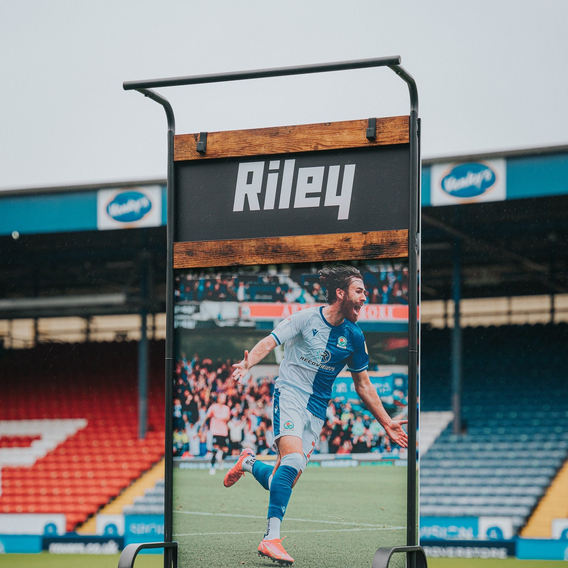 A personalised player display stand with a footballer print, set on a stadium pitch