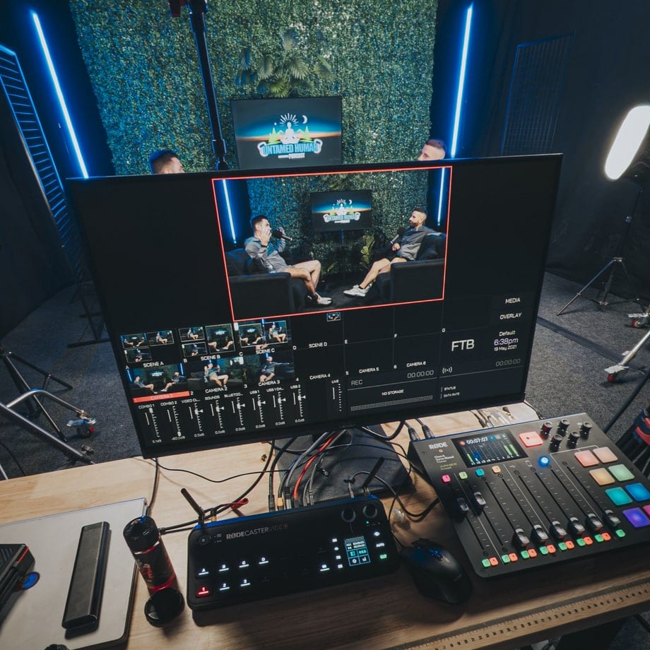 Vision mixer and Rodecaster desk running a two-camera podcast on the green wall set