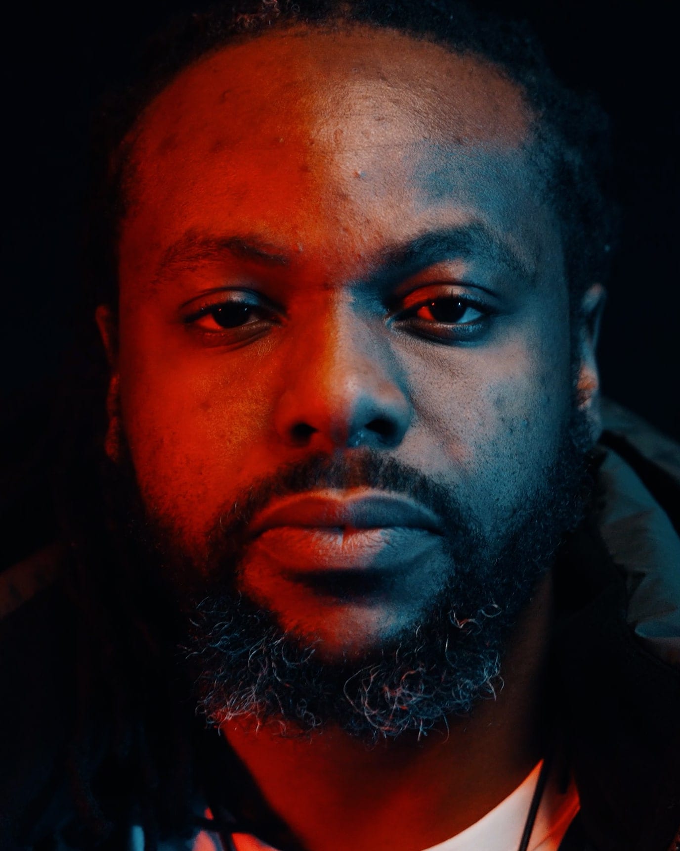 Close-up of an artist under split red and blue light, a still from a Flexxed music video